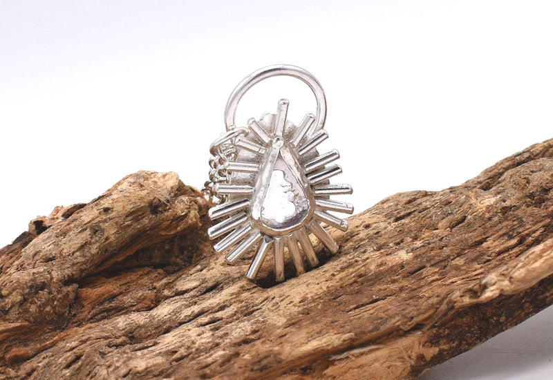 May include: A silver ring featuring a pear-shaped clear stone set in a starburst design.